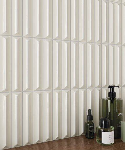 Glossy white geometric wall tiles with bathroom toiletries on a wooden countertop