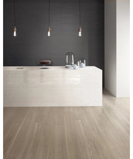 Modern kitchen with white subway tile island, light wood tile flooring, and dark accent wall