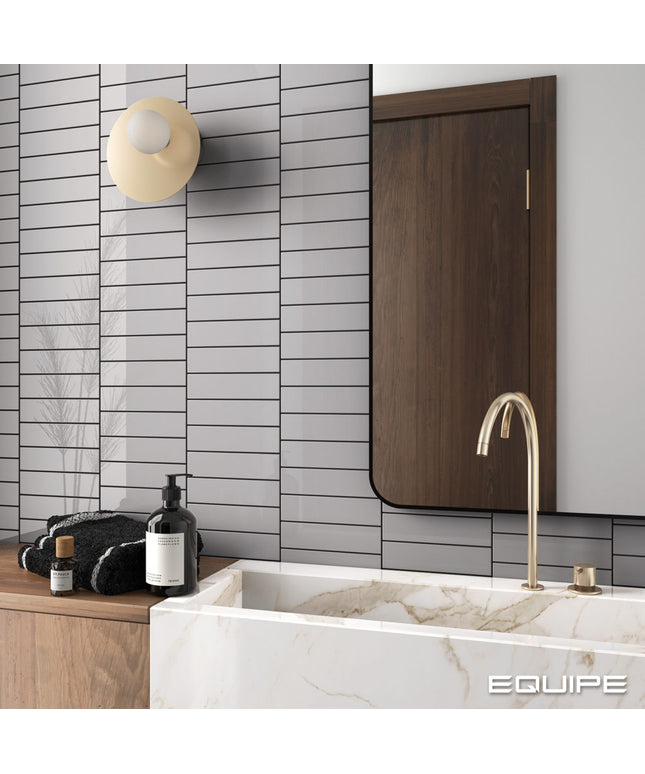 Modern bathroom with marble bathtub, gold faucet, and wooden cabinet.