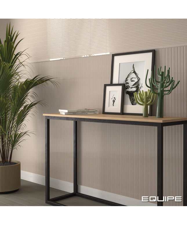 A modern console table with a light wood top and black metal frame, styled in a room setting with framed art, cacti, and a potted plant against a beige ribbed wall.