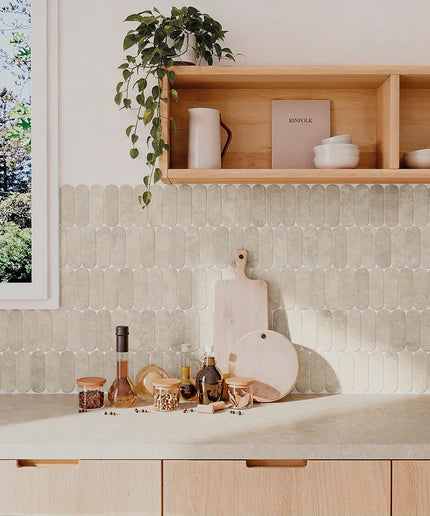 Kitchen counter with cutting boards, bottles, and a plant on a tiled wall.