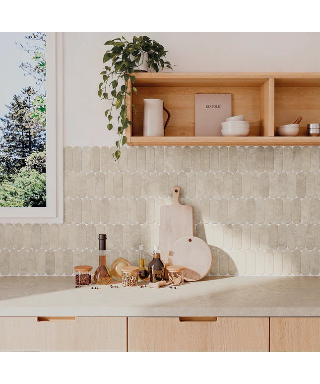 Kitchen counter with cutting boards, bottles, and a plant on a tiled wall.