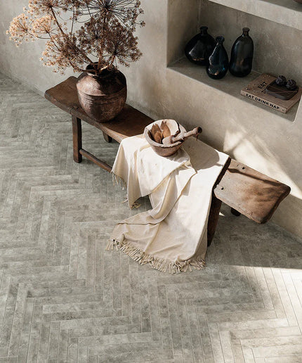 Room interior with wooden bench, vase, and decorative items on a herringbone-patterned floor.