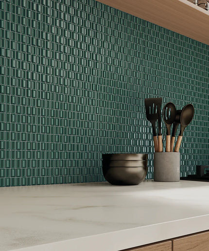 Kitchen counter with green tiled backsplash and utensil holder.