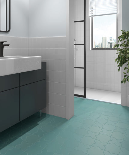 A modern bathroom interior featuring a teal geometric mosaic floor tile, a white rectangular vessel sink, a dark gray floating vanity, and a glass shower door in the background.