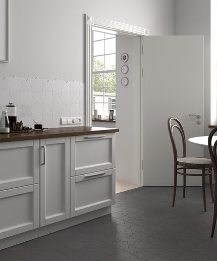 A modern kitchen interior with white cabinetry, a dark wood countertop, gray hexagonal floor tiles, and an open white door leading to another room. No people or animals are present.