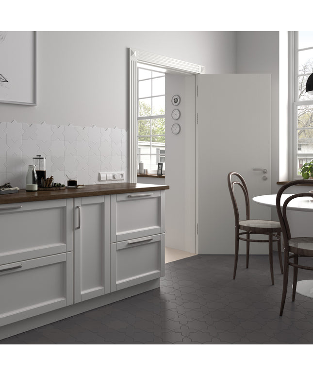 A modern kitchen interior with white cabinetry, a dark wood countertop, gray hexagonal floor tiles, and an open white door leading to another room. No people or animals are present.