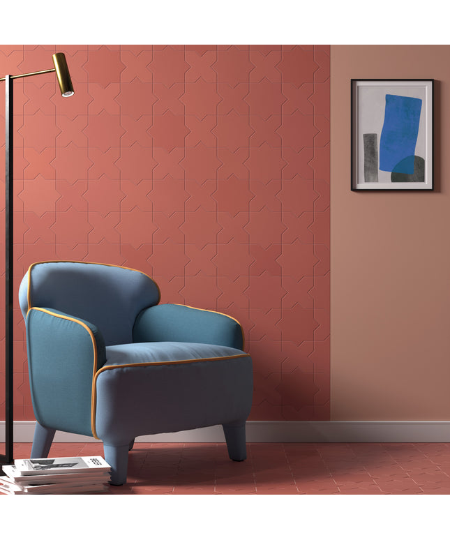 A styled interior scene showing a blue upholstered armchair with gold piping against a terracotta and peach wall, with a black floor lamp, framed abstract art, and a tiled floor.