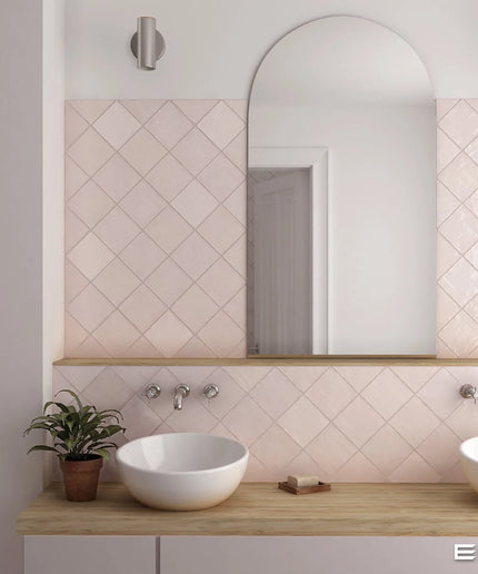 A modern bathroom vanity setup featuring a light pink diamond-patterned tiled backsplash, a large arched mirror, a light wood countertop, and two white ceramic vessel sinks. The image is branded with 'EQUIPE' in the bottom right corner.
