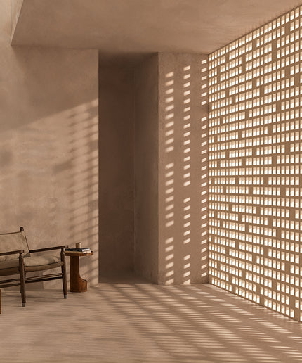 Modern interior with a chair and small table near a textured wall with light filtering through.