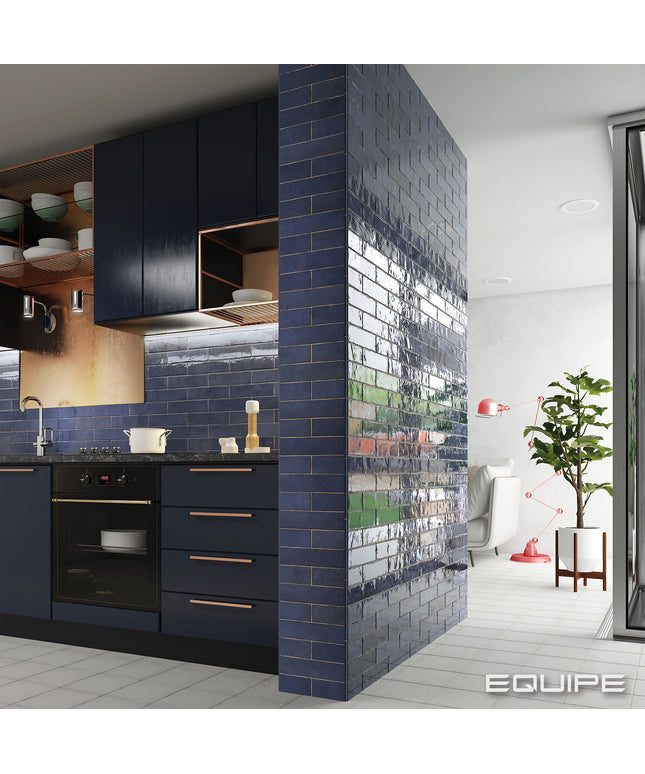 Modern kitchen with dark blue cabinets and a living room with a plant.