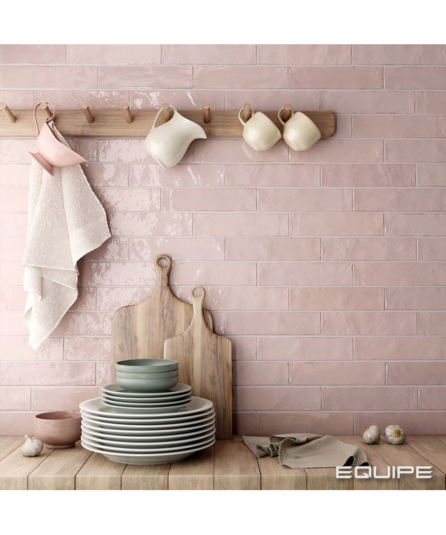 Kitchen setting with pink tiled wall, wooden rack with mugs, and stacked plates on a wooden surface.