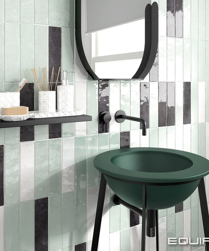 Bathroom with green sink against a tiled wall, featuring the brand 'EQUIPE'.