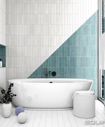 Modern bathroom with white bathtub, teal tiles, and decorative elements.