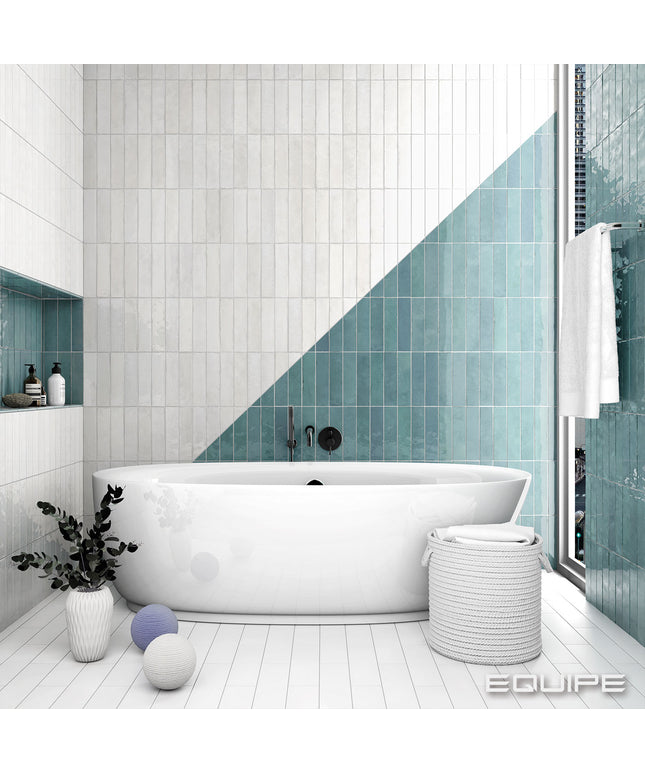 Modern bathroom with white bathtub, teal tiles, and decorative elements.