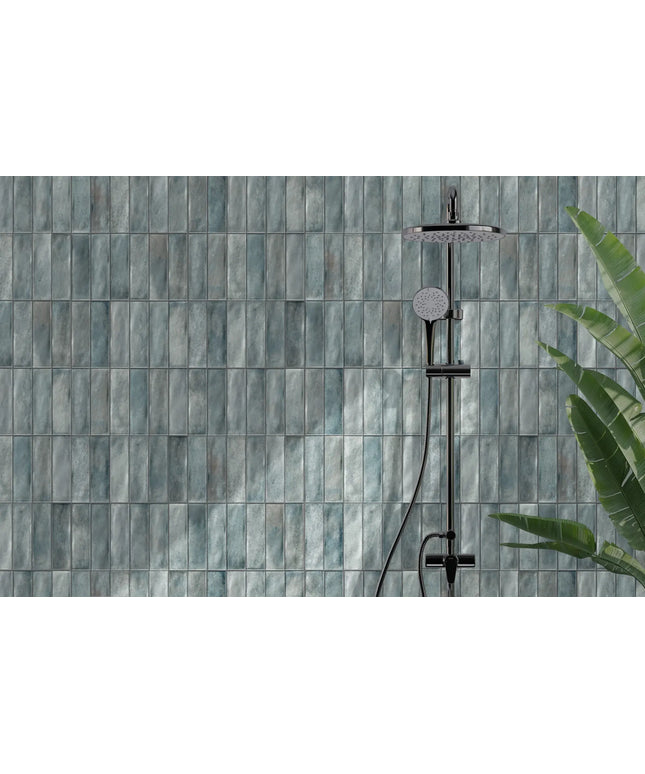 Blue rectangular shower wall tiles with modern shower fixture and green plant