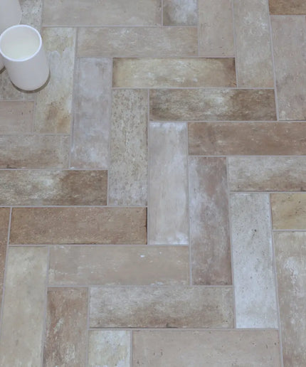 Terracotta herringbone tile flooring with potted plant and white cups decor