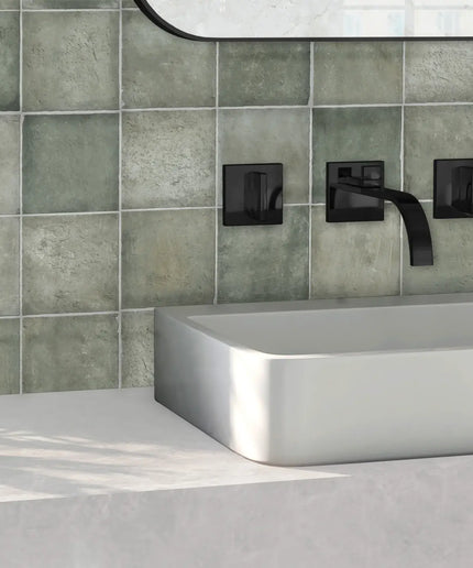 Green ceramic bathroom wall tiles with matte finish behind modern sink and black fixtures