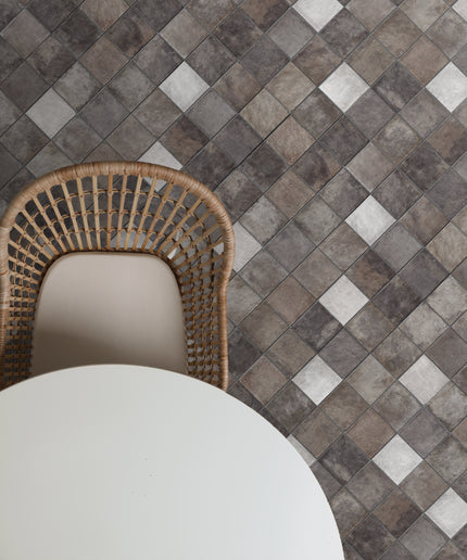 Gray mosaic floor tiles with a woven chair and round white table