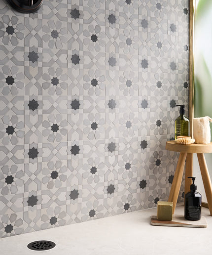 Alpana fes cloud mosaic stone tile. Patterned tiles on a wall with bathroom items on a stool.