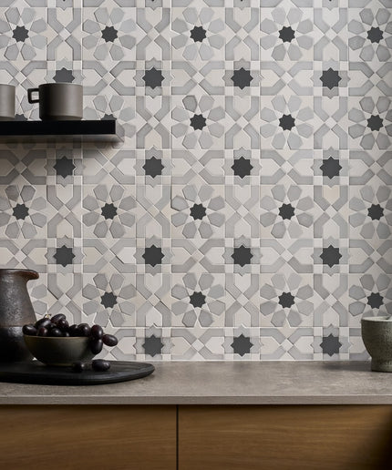 Kitchen counter with decorative tiles and kitchenware against a patterned tile wall.