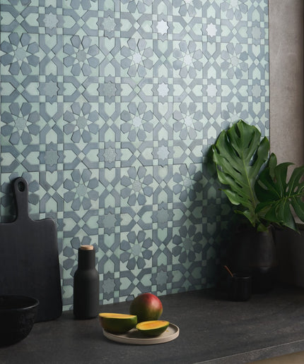 Patterned wall tile with a kitchen setting featuring a cutting board, plant, and fruit.