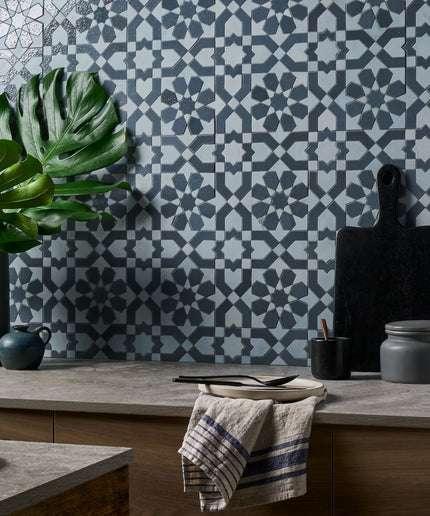 Kitchen with geometric patterned wall tiles, plants, and kitchen utensils.