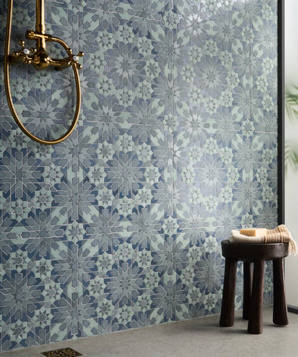 Patterned tiles on a wall with a wooden stool and decorative item in the foreground.