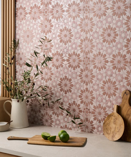 Kitchen counter with cutting board, limes, and pitcher against a patterned wall.
