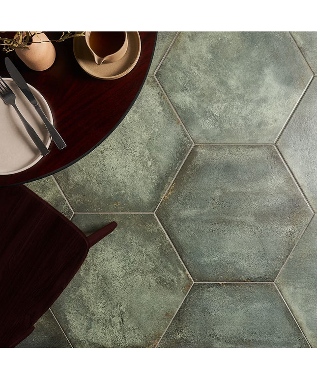 Hexagonal tiles with a rustic finish on a floor, with a table and cutlery in the foreground.