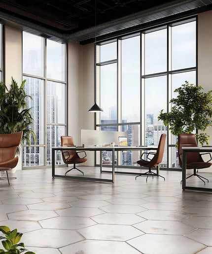 Modern office space with large windows, desks, and chairs.