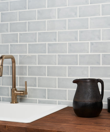 Kitchen sink with bronze faucet against a gray tiled wall