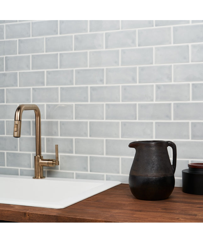 Kitchen sink with bronze faucet against a gray tiled wall