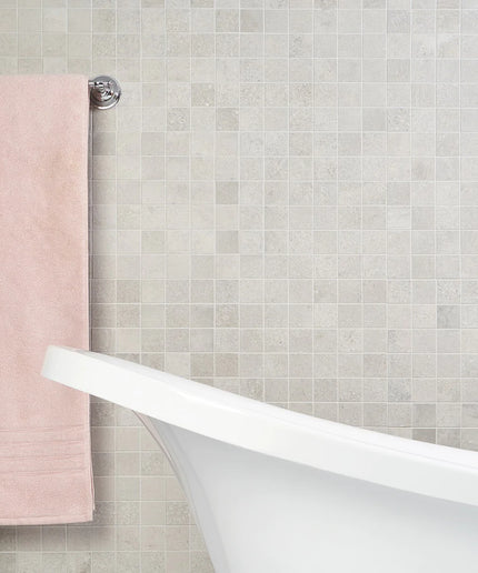 Bathroom with a white freestanding bathtub against a tiled wall with a pink towel. made in the USA