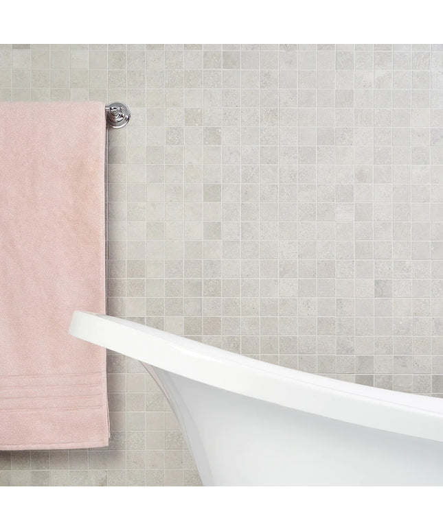 Bathroom with a white freestanding bathtub against a tiled wall with a pink towel. made in the USA