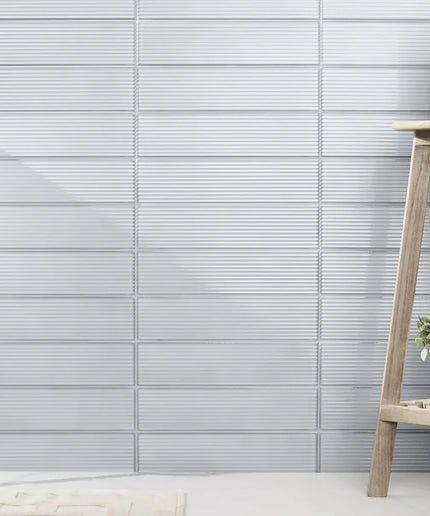 Light blue fluted glossy wall tiles in a modern interior with a wooden shelf and potted plant
