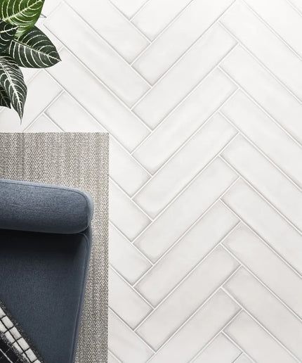 Matte white herringbone tile flooring with a blue chair, rug, and houseplant