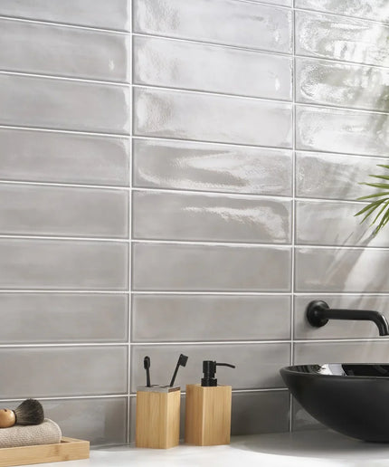 Glossy gray rectangular wall tiles in a modern bathroom with black sink and bamboo accessories