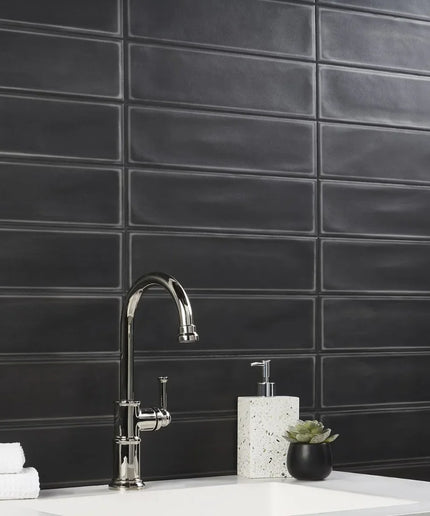 Matte black 4x16 rectangular tiles in a modern bathroom backsplash with chrome faucet