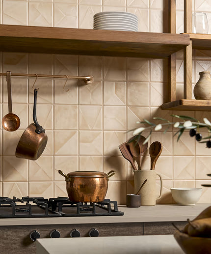 Kitchen with copper pots, wooden spoons, and a tiled wall.