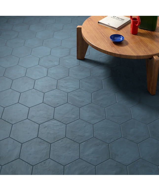 Hexagonal blue tiles on a floor with a wooden table and items on it.