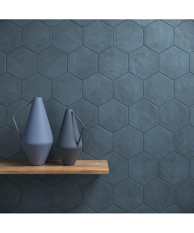 Two gray vases on a wooden shelf against a dark hexagonal tiled wall.
