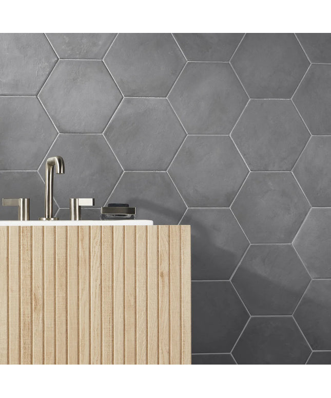 Hexagonal gray tiles on a wall with a wooden cabinet and silver fixtures.