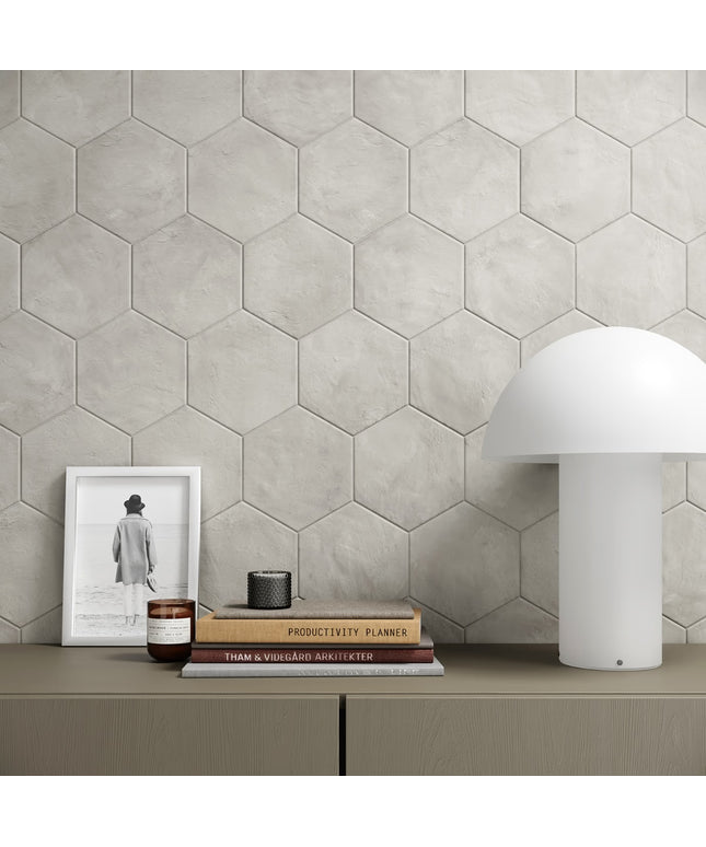 Hexagonal tile wall with a shelf displaying books, a candle, and a lamp.