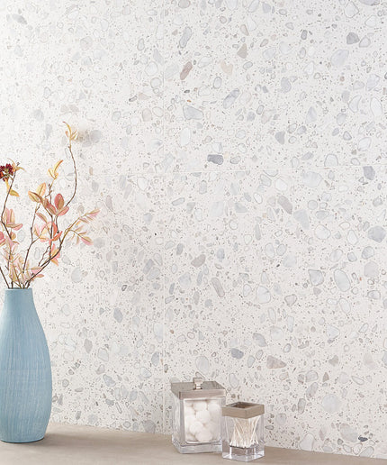 Decorative wall with a textured pattern, featuring a blue vase with flowers and two candle holders.