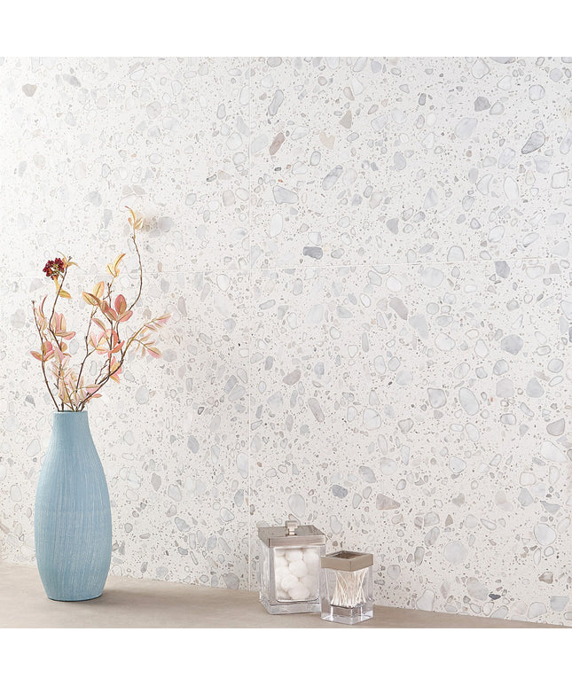 Decorative wall with a textured pattern, featuring a blue vase with flowers and two candle holders.
