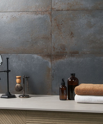 Bathroom counter with towels, bottles, and a mirror against a tiled wall.