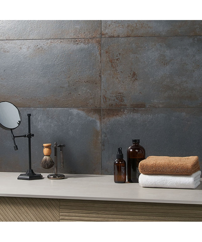 Bathroom counter with towels, bottles, and a mirror against a tiled wall.