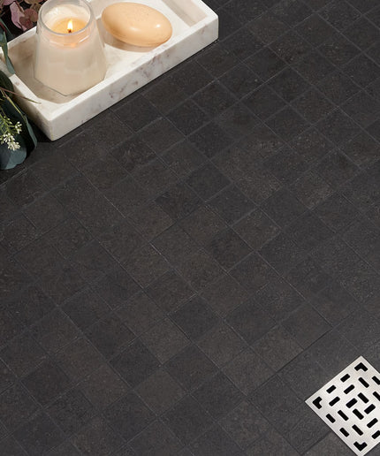 Dark tiled floor with a small white tray holding a candle and soap, next to a decorative plant. made in the USA