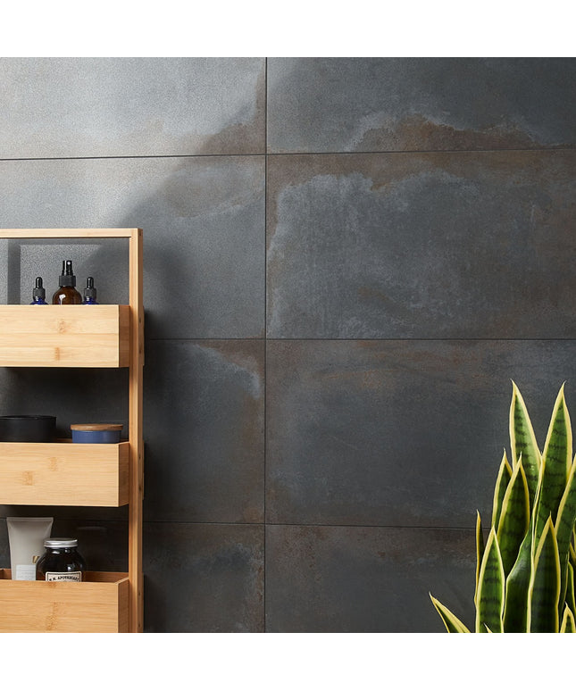 Bathroom setting with wooden shelf against a gray tiled wall, featuring a plant on the right.